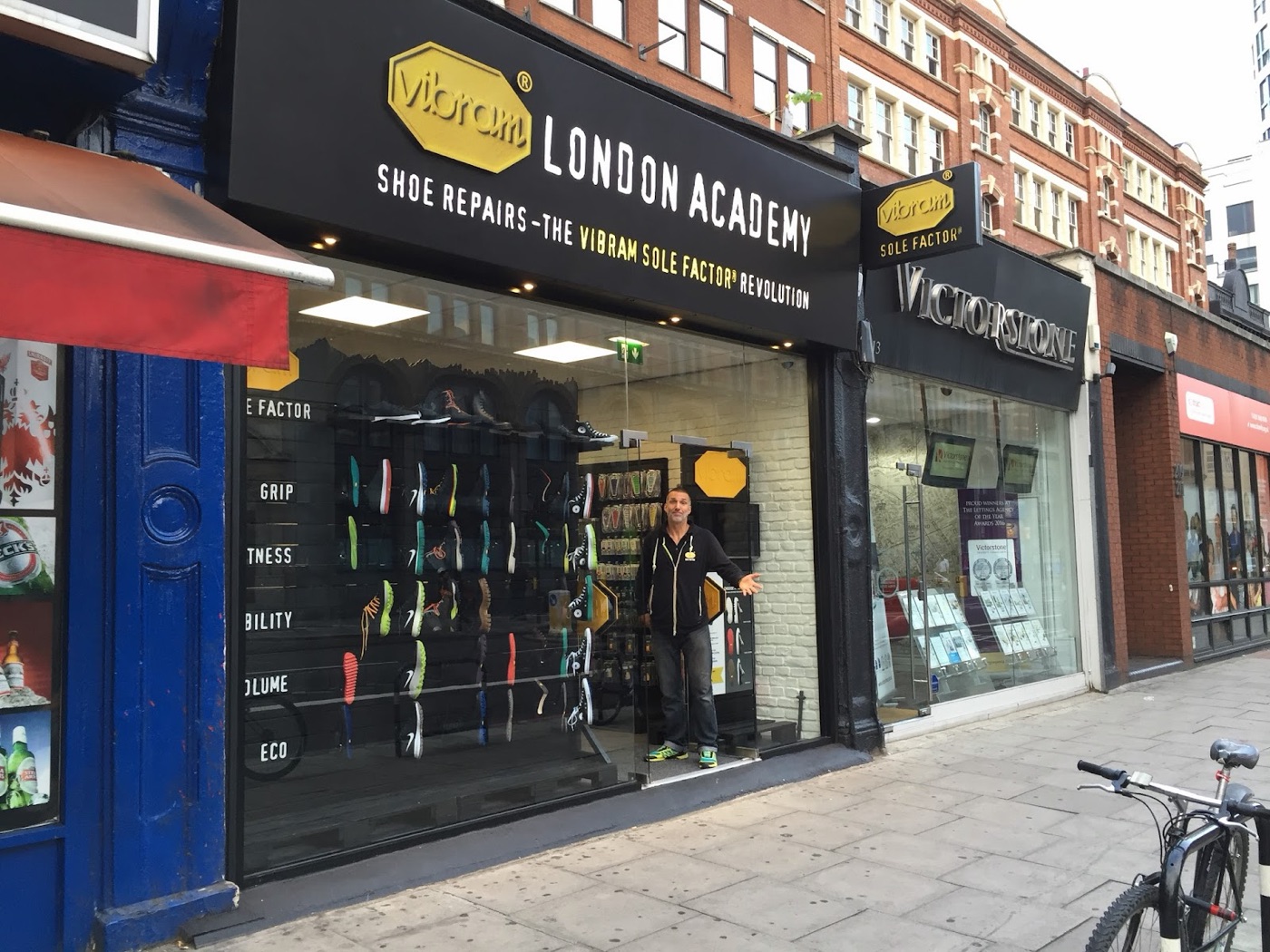 The full Vibram London Academy shopfront on City Road, black frontage with the yellow Vibram octagon sign reading Shoe Repairs, the Vibram Sole Factor Revolution.