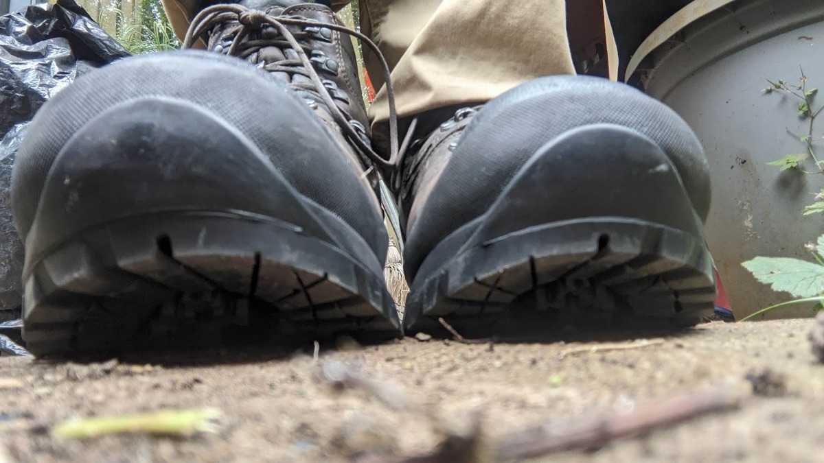A pair of leather walking boots seen from behind, freshly fitted with chunky black Vibram lugged soles by the Academy.